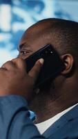 Vertical Business IT technician engaged in a phone call about deep learning tasks, surrounded by a virtual interface showcasing AI research, network connectivity and high tech innovation. Camera B. video