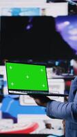 Vertical African American tech enthusiast looking at chroma key screen next to digital interfaces and multimedia visuals, showcasing content creation, mobile technology and global online influence. Camera A. video