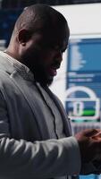 Vertical African american specialist checking big data fintech reports on phone app, examining KPI models for financial insight and performance. Young leader browses smartphone. Camera B. video