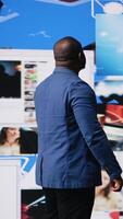 Vertical African American professional browses high tech environment with app icons, infographics and social networking feeds. Showcases big data on social media platforms, digital influence. Camera A. video