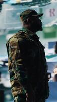 Vertical Black army officer working in a virtual war zone with digital satellite data, using threat detection tools for national safety. Military strategy to ensure control in a mission. Camera B. video
