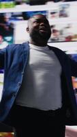 Vertical African american man connected to a global network through mobile devices, opening apps and streaming services platforms. Emphasizing communication and user interface evolution. Camera B. video