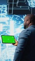 Vertical African american engineer shows tablet with isolated mockup display, examining predictive analytics and neural networks for data processing automation and innovation. Cybernetics. Camera A. video