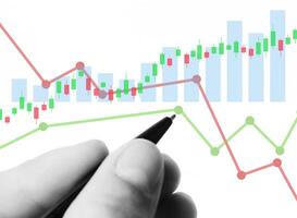 a hand is holding a pen and pointing at a chart photo