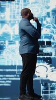 Vertical Black male specialist engaged in AI research interacting with data structures or platforms and smart technology systems. Studies deep learning, cloud computing and predictive analytics. Camera A. video