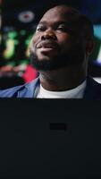 Vertical African american specialist engaging with media dashboards screens, emphasizes networking with AI and technology. Tech driven guy showcases online platforms and internet communication. Camera B. video