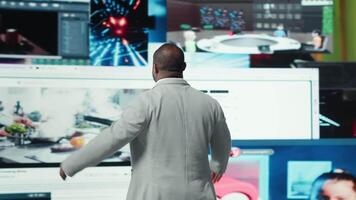 Ecstatic viewer celebrating freedom of unlimited content in virtual space. Delighted african american man with open arms in front of videowall enjoying multiple broadcasting channels, camera A video