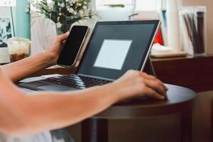 Business woman hands using cell phone while working on laptop. photo