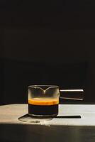 Espresso coffee in a glass cup on a dark background in vertical. photo