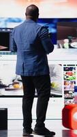 Vertical African American user emphasizing visual concept of online communication, connecting to web platforms and apps. Mobile technology surrounded by social network icons in digital space. Camera A. video