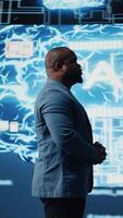 Vertical African american guy reviews smart tech AI systems to interact with cybernetic platforms and AI interfaces, representing the integration of machine learning and predictive analytics. Camera A. video