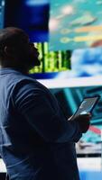 Vertical African american expert exploring tech driven environment with visual data, content feeds and applications. Symbolizing entertainment, social reach and digital transformation. Camera B. video