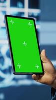 Vertical Black IT specialist examining algorithmic data next to chroma key, using tablet in a high tech environment with futuristic digital visuals. AI smart technology and neural networks. Camera B. video