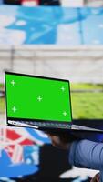 Vertical Professional content creator in a multitasking space holds green screen, leveraging social media, internet big data and cloud systems. Engaging followers to boost digital presence. Camera A. video