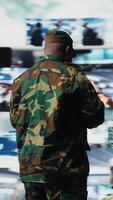 Vertical Armed forces soldier gathers surveillance from digital drone systems, preparing for combat with warfare strategies and battlefield details. War planning operations in command center. Camera A. video