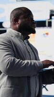 Vertical Black professional administrator examining digital dashboard with finance graphs, working on strategic planning with infographics on gadget. Corporate economy management. Camera B. video