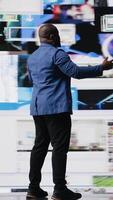 Vertical African American public speaker on stage surrounded by digital visuals, symbolizing a global conference where trends, mobile apps and AI powered content dominate modern communication. Camera A. video