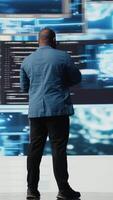 Vertical African american skilled engineer programming for innovation hub, reviewing big data and binary code on the dashboard. IT developer working on programming language algorithm. Camera A. video