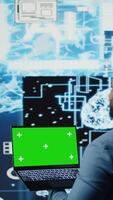 Vertical Black male engineer showing laptop with chroma key display next to predictive analytics immersed in AI brain development and deep learning. High tech cybernetics algorithms. Camera A. video