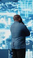 Vertical African American businessman studying digital AI brain interface, symbolizing neural networks, data science and algorithmic thinking. Cybernetics for a high tech futuristic innovation. Camera A. video