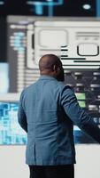 Vertical Black professional software engineer programming for tech innovation, reviewing data and binary code on the dashboard. IT specialist examining programming language for transformation. Camera A. video