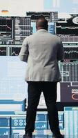 Vertical African american professional reviews financial charts and KPI projections, business performance and innovation with strategic insight through fintech materials and forecasting tools. Camera A. video