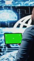 Vertical Black IT specialist examining algorithmic data next to chroma key, using tablet in a high tech environment with futuristic digital visuals. AI smart technology and neural networks. Camera A. video