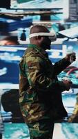 Vertical African american soldier uses virtual reality headset to monitor surveillance footage, using interactive device to guarantee successful national defense mission. War zone operations. Camera A. video