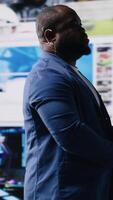 Vertical African American public speaker on stage surrounded by digital visuals, symbolizing a global conference where trends, mobile apps and AI powered content dominate modern communication. Camera B. video