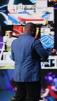 Vertical African american digital creator interacting with high tech visuals and screens, illustrating cloud based systems, e commerce trends and big data in web networking tech environment. Camera A. video