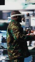 Vertical Black military personnel uses VR glasses to collect intelligence from satellite imagery, working in command control with high tech monitoring tools for a national defense mission. Camera A. video