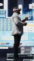 Vertical Young startup administrator reviews big data with virtual reality headset, working hard on business growth to increase profit. Analyzing monthly reports for productivity and success. Camera A. video