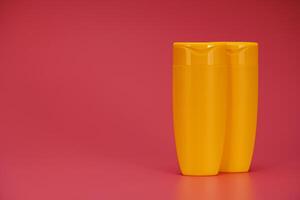 Two Yellow Blank Label Shampoo Bottle or Shower Gel on Pink Background photo