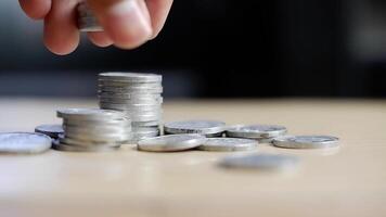 On the desk have coin pile and holding put down coin on it. Concept Planning for spending and accumulating money Including paying taxes. video