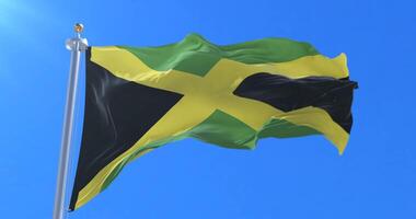 Flag of Jamaica waving at wind with blue sky in slow loop video