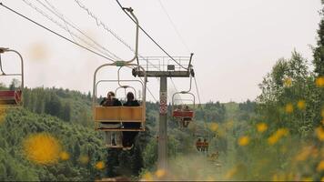 Ukraine lviv 28.06.2025 Open Cable Chairlift Transporting Visitors Over Dense Summer Forest, Red and Yellow Seats Gliding Above Tree Canopy in Green Carpathian video