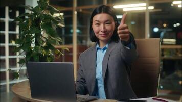 Asian Korean Chinese Japanese woman working with laptop typing computer girl smiling businesswoman business female in office employer showing gesture thumb up approval manager worker recommendation video