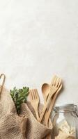 Wooden Utensils in Burlap Bag with Green Leaves near Glass Jar on Light Surface representing Zero Waste Living photo