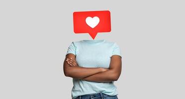 A person stands confidently with crossed arms, their head replaced by a large heart icon, symbolizing social media likes and positive engagement. photo