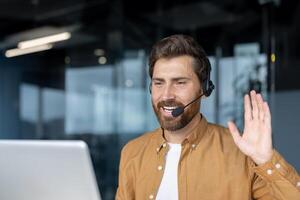 Confident man on call in modern office, wearing headset, engaging in communication, waving. Represents remote work, professional interaction, online meeting, digital connection. photo