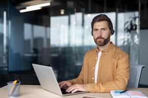 Mature business man using headset and laptop in office. Depicts professional communication, focus, and efficiency ideal for customer support or remote work scenarios. photo
