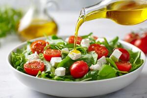 Pouring olive oil over fresh spinach salad with cherry tomatoes and feta cheese photo