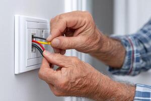 Electrician installing cable in a network wall socket photo
