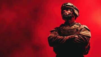 Soldier stands confidently in tactical gear against a vivid red background, embodying strength and determination during a dramatic moment of contemplation photo