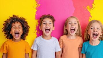 Group of four children with joyful expressions celebrating in front of a vibrant pink and yellow wall during a sunny day in a park setting photo