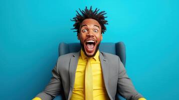 Excited man in a suit with yellow shirt sitting in a blue armchair against a bright background expressing joy and enthusiasm photo