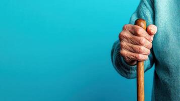 Elderly person holding wooden cane against a bright blue wall during calm indoor moment showing strength and resilience in later life photo