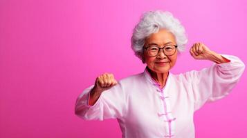 Cheerful elderly woman with glasses celebrates fitness in vibrant pink backdrop during a wellness event in the afternoon light photo
