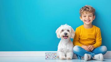 Joyful child and playful dog sitting together against a vibrant blue wall in a cheerful indoor setting during daytime photo