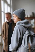 Teen boy experiences conflict and emotions while leaving father at home after an argument photo